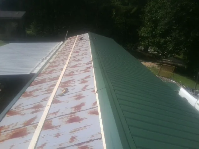 Old rusted panels beside newly installed green metal roofing — Wind Damage Roof Repair by Roofing Brothers in Murphysboro