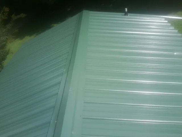New green metal panels meeting at the ridge of a roof — Flat Roof Repair work by our crew in Murphysboro