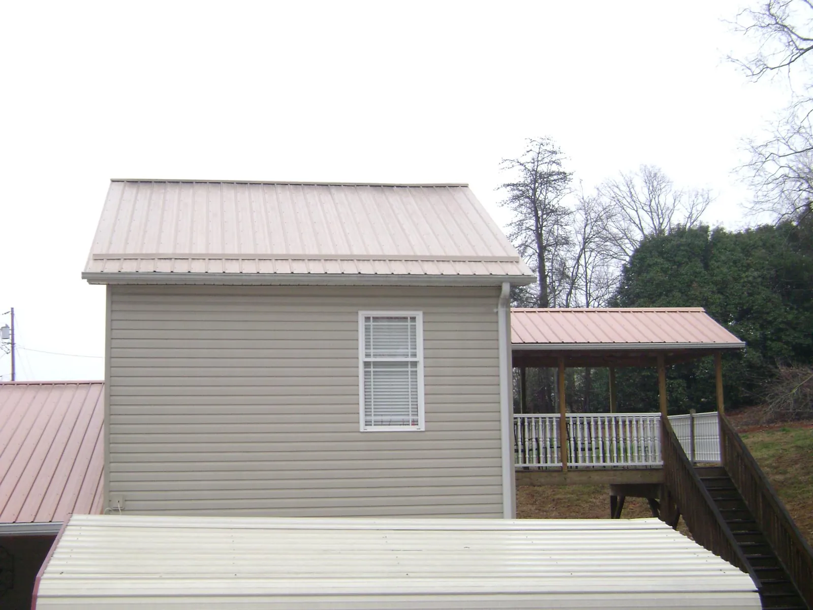 Tan metal roofs on a two story addition and attached porch, from a Roof Replacement job in Murphysboro