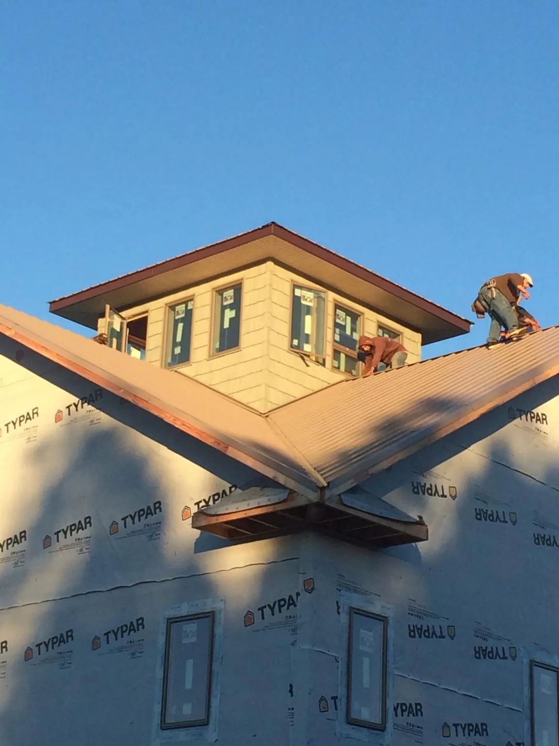 Roofers working around a rooftop cupola on a new metal roof at sunset — Roof Waterproofing in Murphysboro by Roofing Brothers